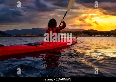 Aventure fille pagayant sur un kayak rouge vif Banque D'Images