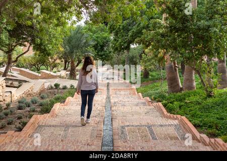 Espagne; novembre 2020: Personne marchant dans les jardins arabes à l'intérieur d'une ancienne fortification, jardins islamiques traditionnels avec des allées et de l'eau coulant à Alcazaba, Banque D'Images