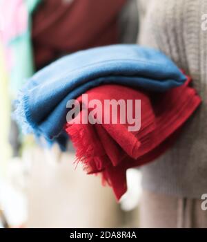 Gros plan sur une écharpe colorée, gros plan sur des vêtements en cachemire bleu et rouge, morceau de tissu en laine, mise au point douce, bokeh flou sur fond gris Banque D'Images