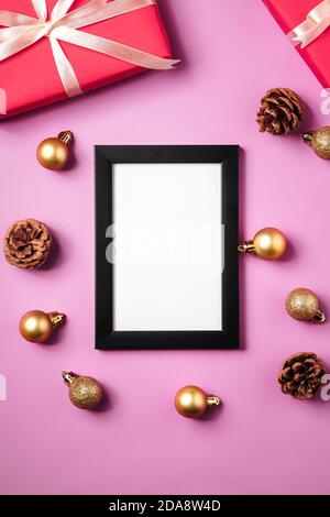Noël composition minimale avec cadre photo vide. Décoration dorée, boîtes-cadeaux et décorations en forme de cônes de pin. Modèle de carte de vœux Banque D'Images