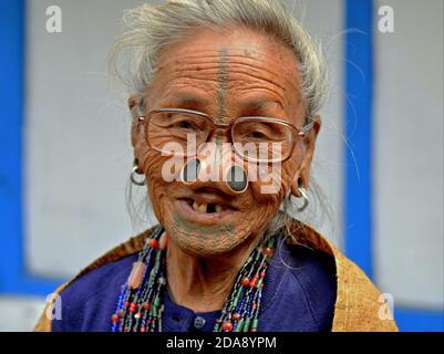La vieille femme tribale indienne du Nord-est Apatani avec des bouchons de nez en bois noir et un tatouage traditionnel porte des lunettes modernes et des sourires pour l'appareil photo. Banque D'Images