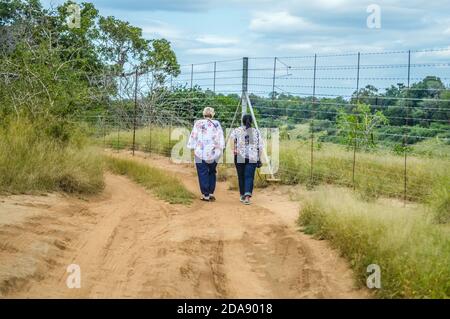 Une vieille femme italienne et un adulte femme indienne se promener le long de la clôture en Marloth park le long du parc Kruger Banque D'Images