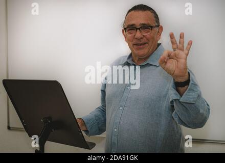 un homme adulte avec des lunettes fait une présentation à un lutrin et en levant la main Banque D'Images