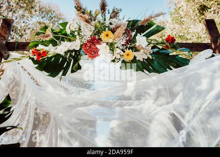 Auvent avec arrangements floraux et mousseline soyeuse soufflant dans le vent. Banque D'Images