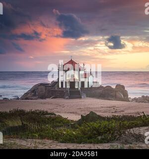 Coucher de soleil sur la plage avec une église sur la plage (Église de Senhor da Pedra) Banque D'Images