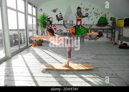 Femme pratiquant le yoga sur un panneau SUP intérieur Banque D'Images