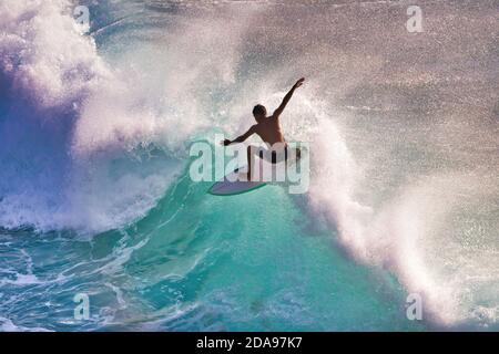 Surfeur plein d'action en silhouette sur une vague de haute énergie à Maui. Banque D'Images