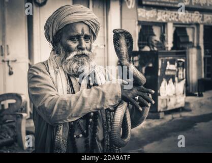 saint baba moine saint hypnotisez un serpent Cobra kundalini avec flûte sur la rue de varanasi, Inde. Banque D'Images