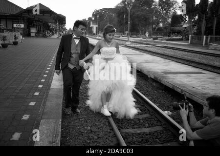 Emplacement inhabituel pour une séance photo avant mariage avec future mariée et marié sur la voie ferrée à une gare. Hua Hin Thaïlande. Noir et blanc Banque D'Images