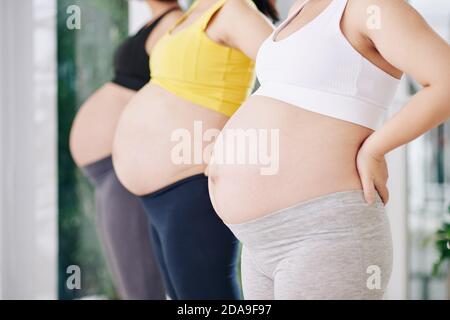 Image rognée de femmes enceintes debout dans la rangée après avoir assisté à la réunion cours de yoga au club de santé Banque D'Images