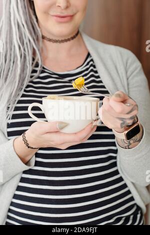 Image rognée d'une jeune femme enceinte souriante mangeant fraîche et saine salade de fruits Banque D'Images