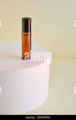 Flacon compte-gouttes - verre ambré pour flacons de parfum non étiquetés sur podium blanc. Banque D'Images