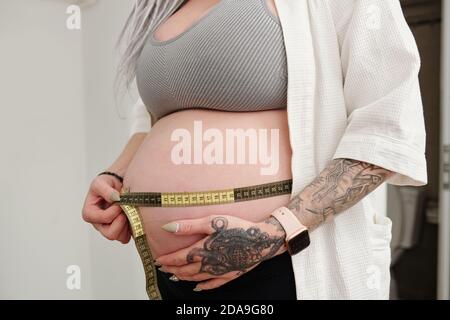 Image rognée d'une jeune femme enceinte mesurant son ventre Banque D'Images