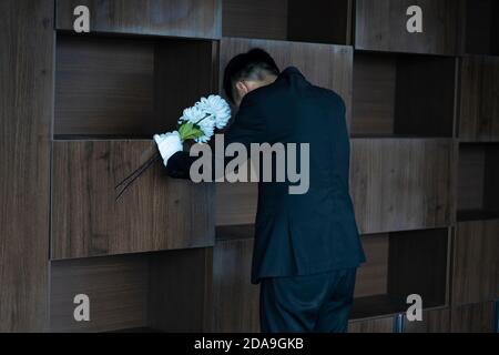 Pleurer avec des fleurs aux funérailles Banque D'Images