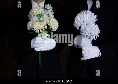 Deuil tenant des fleurs aux funérailles Banque D'Images