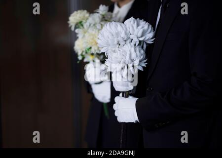Deuil tenant des fleurs aux funérailles Banque D'Images