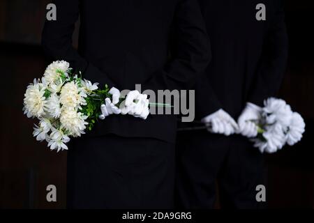 Deuil tenant des fleurs aux funérailles Banque D'Images