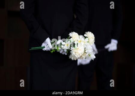 Deuil tenant des fleurs aux funérailles Banque D'Images
