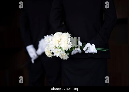 Deuil tenant des fleurs aux funérailles Banque D'Images