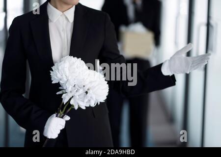 Deuil tenant des fleurs aux funérailles Banque D'Images