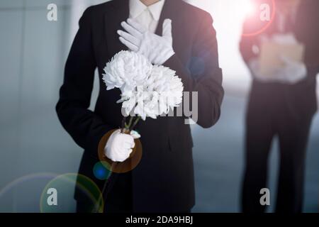 Deuil tenant des fleurs aux funérailles Banque D'Images