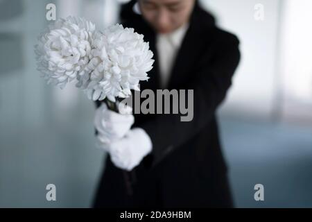 Deuil tenant des fleurs aux funérailles Banque D'Images