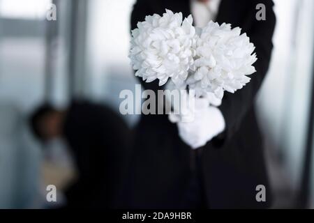 Deuil tenant des fleurs aux funérailles Banque D'Images