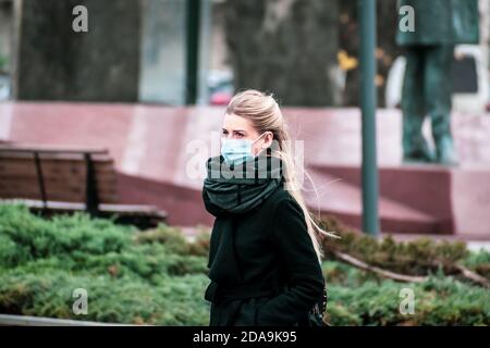 Belle fille blonde portant un masque et marchant dans la ville Pour faire du shopping pendant l'épidémie de Covid ou de coronavirus Banque D'Images