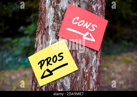 Pour et contre mots écrits sur des papiers sur un arbre avec des signes de flèche. Décider ou analyser entre les avantages et les inconvénients. Banque D'Images