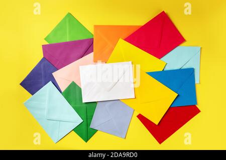 De nombreuses enveloppes de différentes couleurs, prises en hauteur sur fond jaune Banque D'Images