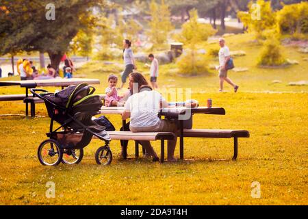 Montréal, Canada - juin 2018 : la famille canadienne avec sa mère, son père et son enfant s'assoit au banc du parc du Mont-Royal à Montréal, au Canada, sur un somme ensoleillé Banque D'Images