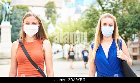 Femme amis marchant avec masque de visage après la réouverture de verrouillage - Nouveau concept d'amitié normale avec les filles passant du temps ensemble Rues de la ville - Soci Banque D'Images