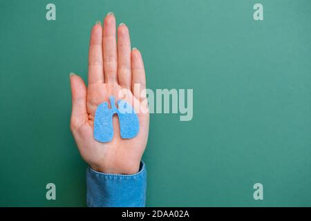 Journée mondiale de la pneumonie. Les mains des femmes tiennent la silhouette des poumons. Pose à plat. Arrière-plan vert. Copier l'espace. Banque D'Images