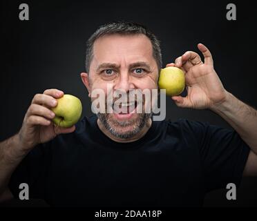 Portrait d'un homme d'âge moyen émotionnel avec des pommes vertes Banque D'Images