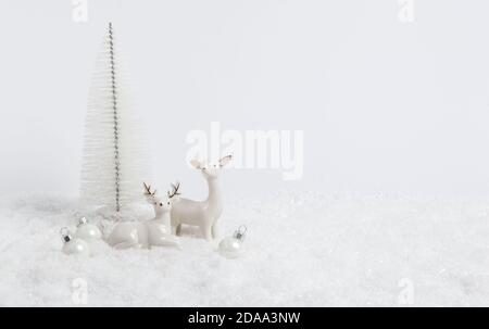 Carte de Noël blanche. Deux rennes dans la neige sur fond blanc avec boules et arbre de Noël. Composition d'hiver monochrome avec espace de copie f Banque D'Images