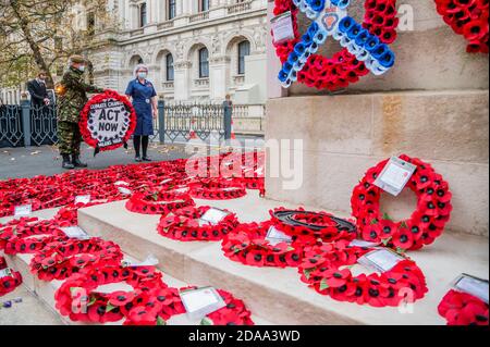 Londres, Royaume-Uni. 11 novembre 2020. «honorer leur sacrifice»: L'ancien combattant de la rébellion d'extinction et une infirmière payer respecte au Cenotaph avec bannière Avertissement changement climatique signifie guerre. Cette action intervient alors qu’un rapport commandé par le ministère de la Défense, publié en juin dernier, met en garde contre la « reconnaissance croissante du fait que le changement climatique risque d’aggraver les menaces existantes pour la paix et la sécurité internationales ». Extinction révolte des rébellions au Cenotaph au sujet du risque de conflit futur résultant du changement climatique. Crédit : Guy Bell/Alay Live News Banque D'Images