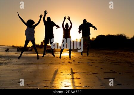 silhouette d'un groupe de jeunes amis heureux tout en vous amusant de sauter et de courir sur la plage à coucher de soleil pendant les vacances d'été Banque D'Images