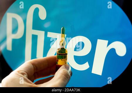 Société pharmaceutique Pfizer de vaccins contre le coronavirus. Logo Pfizer avec vaccin à main. Banque D'Images
