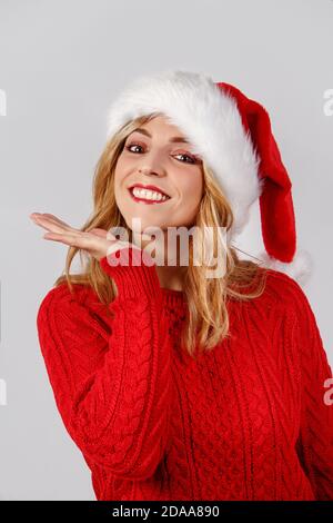 Jeune femme au chapeau de santa souriant isolée sur gris Banque D'Images