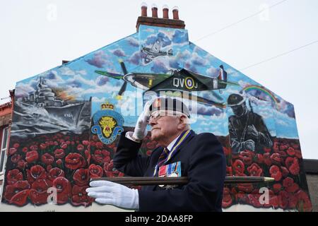 Eric Howden BEM, 76 ans, président de la Légion britannique de Redcar, qui a servi avec le corps royal de l'Ordnance, devant une fresque commémorative de la guerre à Redcar, dans le North Yorkshire, devant un silence de deux minutes pour se souvenir des morts de la guerre le jour de l'armistice. Banque D'Images