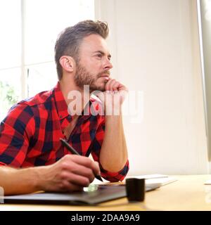 Portrait de profil latéral de l'homme pensant assis au bureau avec stylet Banque D'Images