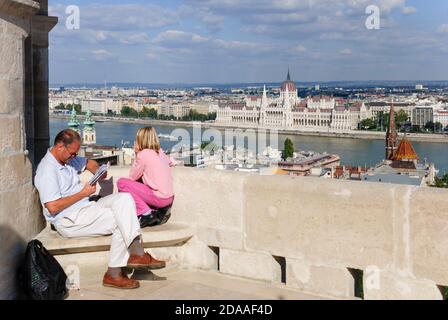 Europe, Hongrie, Budapest.Vue sur le bâtiment du Parlement de l'autre côté du Danube depuis le bastion de Fishermans à Buda.Touriste lisant un guide. Banque D'Images