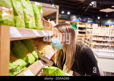 Femme en tant que client avec un masque facial tout en faisant des achats pour épicerie bio au supermarché Banque D'Images