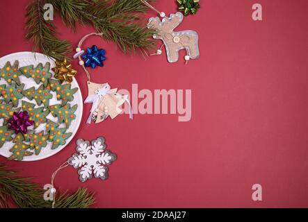 Assiette avec gâteaux de Noël sous forme d'arbres de Noël avec décoration de Noël sur fond rouge.gros plan, espace copie. Orientation horizontale Banque D'Images