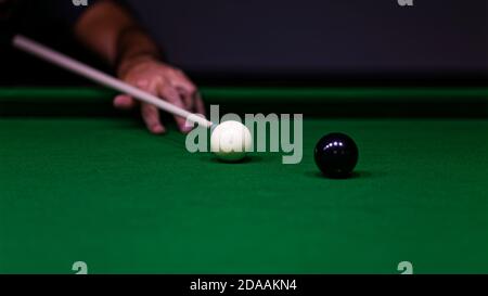 Homme essayant de frapper la balle dans le billard. Mise au point peu profonde. Banque D'Images