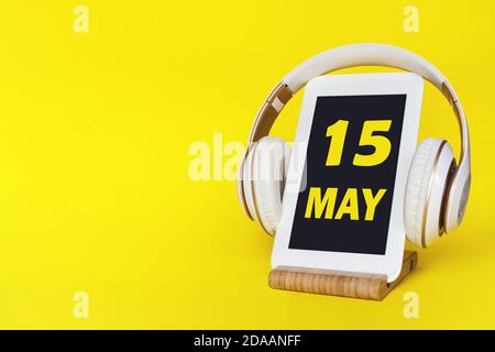 15 mai. Jour 15 du mois, date du calendrier. Casque élégant et tablette moderne sur fond jaune. Espace pour le texte. Enseignement des concepts, technologie, li Banque D'Images