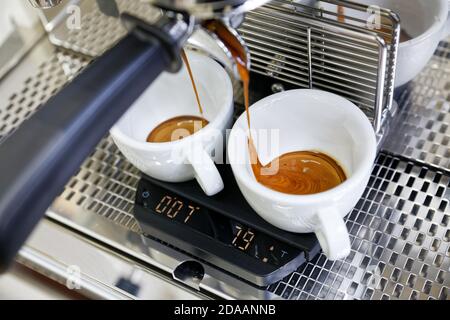 Préparation du café dans la machine à café. Espresso versé dans deux tasses blanches. Banque D'Images