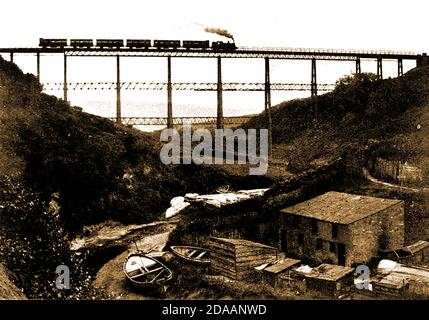 Un train à vapeur traversant l'ancien viaduc de chemin de fer victorien au-dessus de la vallée de Dale House, Staithes, Whitby, North Yorkshire UK (concepteur John Dickson). Il a été construit à partir de fer et de béton pour transporter le chemin de fer Whitby, Redcar et Middlesbrough Union Railway au-dessus de la vallée en 1875, mais n'a ouvert qu'en 1883. En raison de la catastrophe du pont de Tay en 1879, les renforts latéraux supplémentaires vus dans la photo ont été ajoutés plus tard. Une cloche a également été ajoutée pour la sécurité dans et a sonné quand il y avait des vents forts, ce qui signifie une limite de vitesse de 20 mph. Le viaduc a été démoli en 1960 Banque D'Images