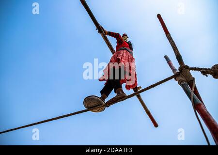 une fille indienne interprète des acrobaties de rue en marchant sur la corde serrée au festival de chameau de pushkar. Banque D'Images