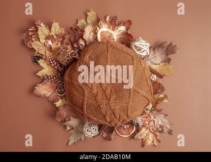 Composition d'automne avec feuilles, cônes de pin et élément tricoté rond sur fond marron. Banque D'Images